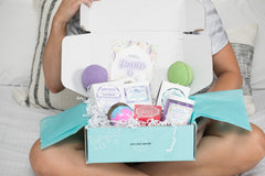 woman holding Bath Bevy Subscription box with bath bombs, whipped soap scrub, bar soap and bath salts