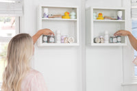 blonde woman touching whipped soap scrub on a bathroom shelf with other bath bevy subscription products