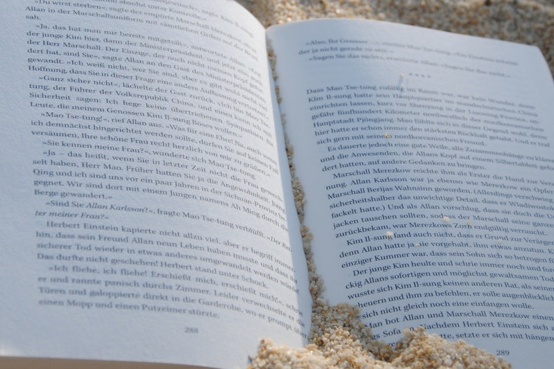 A beach scene with a subscription box from BookTIDE featuring great reads and colorful glass floats