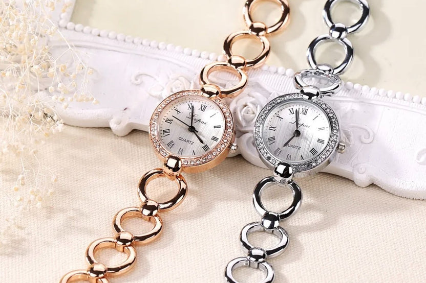One gold and one silver timex watch with metal circle link giving a bracelet impression with a watch face attached. Elegant timepiece