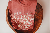 Our cozy mauve-colored tee, adorned with a heartwarming message inspired by the beloved verse John 3:16: "For God So Loved the World"