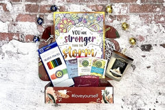 The Stress Relief Adult Coloring Book Box will include a book, an adult coloring book, colored pencils, as well as 2 - 3 self-care products.