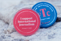 Two pins. One reads "I support international journalism," and the other "Fellow Travelers Club Member."