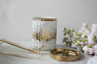 A luxurious candle from the Wickbox monthly subscription box beside floral accents and candle care tools