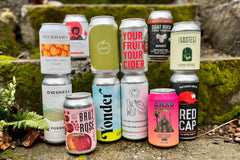 12 cans of cider stacked in front of an old stone staircase. 
