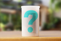 A semi transparent film roll container with a teal question mark, indicating it is a mystery roll of expired film