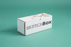 SketchBox subscription box featuring art supplies like markers, a notebook, and a brush for creative projects