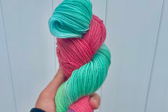 Close up photo of a hand dyed skein of sock weight yarn against a solid background. The skein is twisted and shows a variety of color.