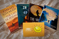 Brown box filled with a diverse collection of books in multiple genres, including crime thrillers, romance, and fantasy