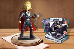 A Sculpted Thor Figurine holding his iconic hammer and a deck of Avengers Playing cards sitting on a wooden table.
