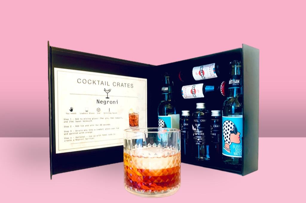 A Cocktail subscription box displaying a negroni cocktail in front of a gift box from Cocktail Crates