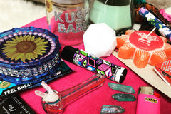Items from The Stoney Babe subscription box including a water pipe, a lighter, an empty jar, and various candles.