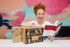 Owl Post Books YA Imagination Box. Three new hardcover books delivered monthly. Picture shows woman smiling with box and books.