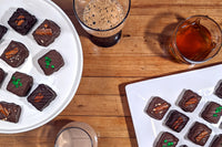 Overhead image of brownie bites on plates, with glasses of Guinness, Bourbon, and Irish Cream next to the plates.
