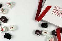 Image of a box of Nettie's Brownies with a red ribbon and an assortment of brownie bites spread across a table.