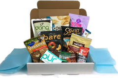 Box filled with snacks such as snackimals, boom chicka pop, back to nature, stacys pita chips, dang, pur gum, health warrier chia bar