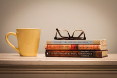 A stack of used books in front of a Used Books Monthly subscription box showcasing a book subscription service