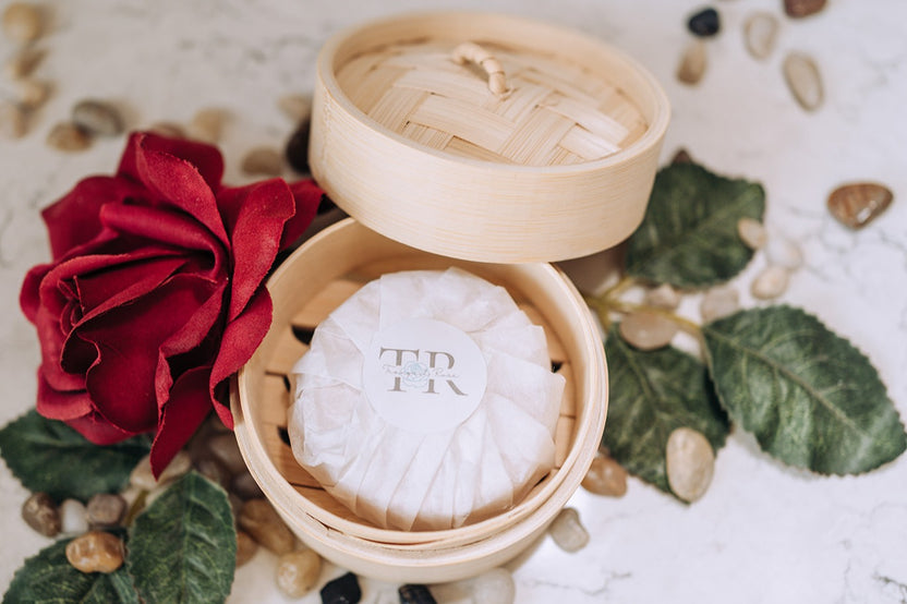 Tranquil Rose handcrafted soap displayed in a bamboo steamer with rose petals, creating an elegant natural bath setting.