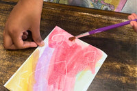Child engaging in a watercolor activity from the Activity Trunk, painting with vibrant colors on paper