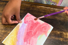 Child engaging in a watercolor activity from the Activity Trunk, painting with vibrant colors on paper