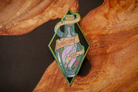 Rainbow anodized metal, hard enamel pin depicting Unicorn hair in a translucent enamel bottle. Printed details and scroll.