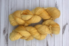 Close up photo of a hand dyed skein of sock weight yarn against a solid background. The skein is twisted and shows a variety of color.