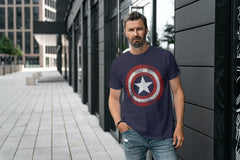 Man in a downtown setting next to a building. He is wearing an iconic Captain America Shield Tshirt.