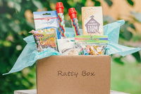 A Ratty Box subscription box filled with ring chews, rope toys, banana chips and other supplies for rats.