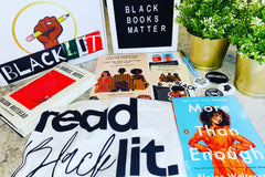 Books, a tote bag, a box with the black power fist holding a pencil and the word BlackLit, a felt board, and stickers.