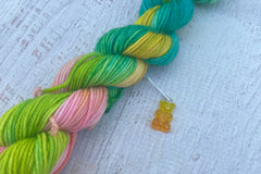 A mini Skein of Hand Dyed Merino Sock Weight Yarn and a coordinating stitch marker. Suitable for knitting and crocheting 