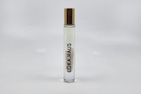 Tall bottle with gold cap: LOKA.HAUS's 'Intensity Parfum Roller'. Luxurious scent, crystal clarity. Elegance rolls on.