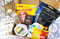 An open Sleek Treat subscription box filled with snacks, including chocolate cups, gummies, cheese crisps and a granola bar.
