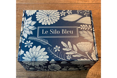 Custom Le Silo Bleu gift box showing the logo on top, Blue box with flowers sitting on a wooden table.