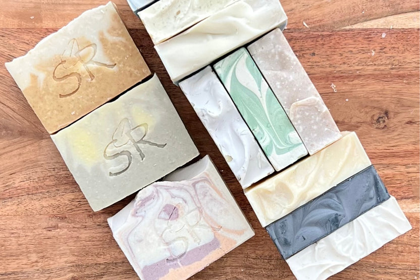 Four different types of Soothing Remedies Bar Soap Boxes on a wooden table, perfect as a gift.