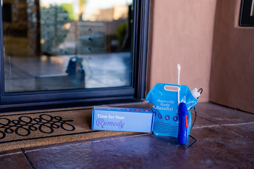 Remedy kit shown in front of door. Application bag with sprayer attached, sitting next to shipping/storage box.