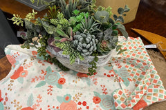 Arrangement of wood and paper handmade plants and a reversable apron. The apron is pink rust and blue. 