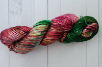 A Skein of Hand Dyed Silk Yarn in Worsted Weight with some green and red and various colors of speckles 