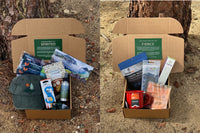 Wild Woman Box subscription boxes stacked on a mountain ledge with a scenic view in the background