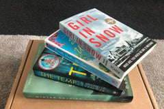 Brown subscription box filled with four surprise mystery books, featuring captivating stories and intriguing plots for genre enthusiasts.