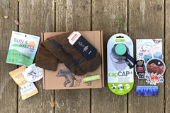 Wild Woman Box subscription boxes stacked on a mountain ledge with a scenic view in the background