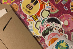 Pic shows assortment of stickers as an example of what could come in a STICKERS ONLY pack, as well as some stickers shown on a laptop case.