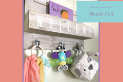 Wall sign that displays books and toys designed specifically for four month old baby.  contains a teether, a fabric block toy and more. 