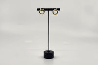 Elegant gold-plated earrings by LOKA.HAUS, displayed on a sleek black stand. Sustainable fashion, ethical luxury for social impact.