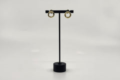Elegant gold-plated earrings by LOKA.HAUS, displayed on a sleek black stand. Sustainable fashion, ethical luxury for social impact.