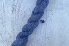A mini Skein of Hand Dyed Merino Sock Weight Yarn and a coordinating stitch marker. Suitable for knitting and crocheting 