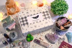 Owl and Moon subscription box is surrounded by 2 succulent plants, various crystals and a buddha statue with candle.