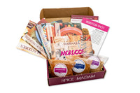 An open Spice Madam monthly subscription box featuring bags of Moroccan spices and recipe cards for cooking adventures