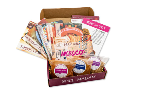 An open Spice Madam monthly subscription box featuring bags of Moroccan spices and recipe cards for cooking adventures