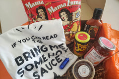box filled with spicy food items to heat up the month of August and includes hot sauce, t-shirt, spicy sweets and condiments. 