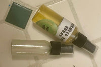 Two small spray bottles lie next to each other against some tiles. The bottle's label reads, "scented body spray."